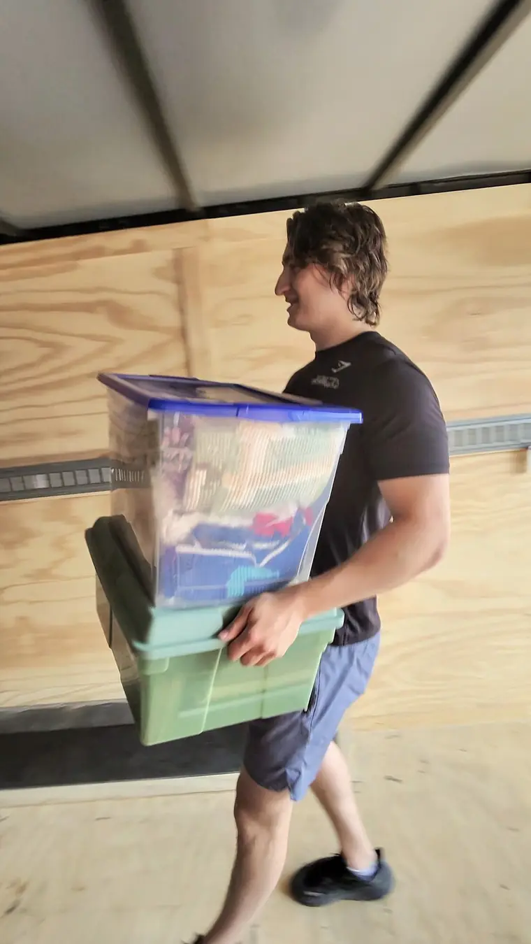 Fast Track Movers crew member carrying storage bins inside the moving truck